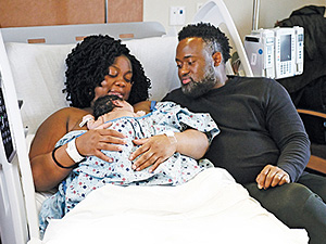 Couple sitting with newborn baby in a labor and delivery suite at Mount Sinai South Nassau