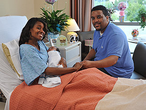 Couple sitting with newborn baby in a labor and delivery suite at the Mount Sinai South Nassau maternity unit